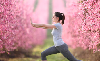 Woman doing tai chi exercise in a pink flowered field