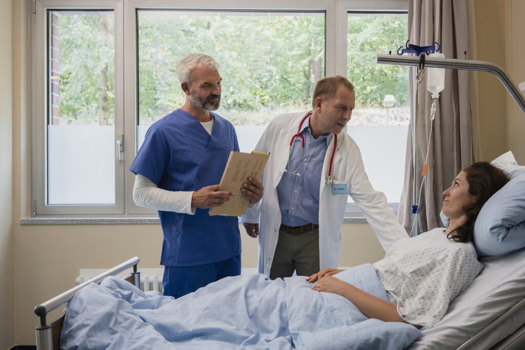 Doctors making rounds, talking with patient in hospital room