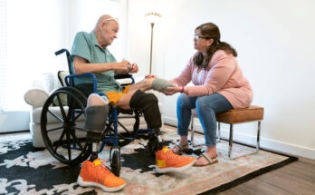 A senior man with amputations gets help from a nurse at home