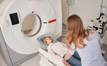 Mature female patient lies on CT or MRI bed moved inside the machine
