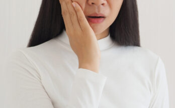 woman touches her cheek with symptoms of pain and suffering on isoleted white background.