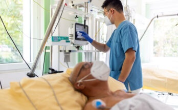 Nurse checking the monitor in the intensive care showing the patient's vital signs. Nurse checking the monitor in the hospital room to see how the senior male patient is doing.