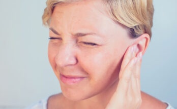 young female having ear pain touching her painful head earache