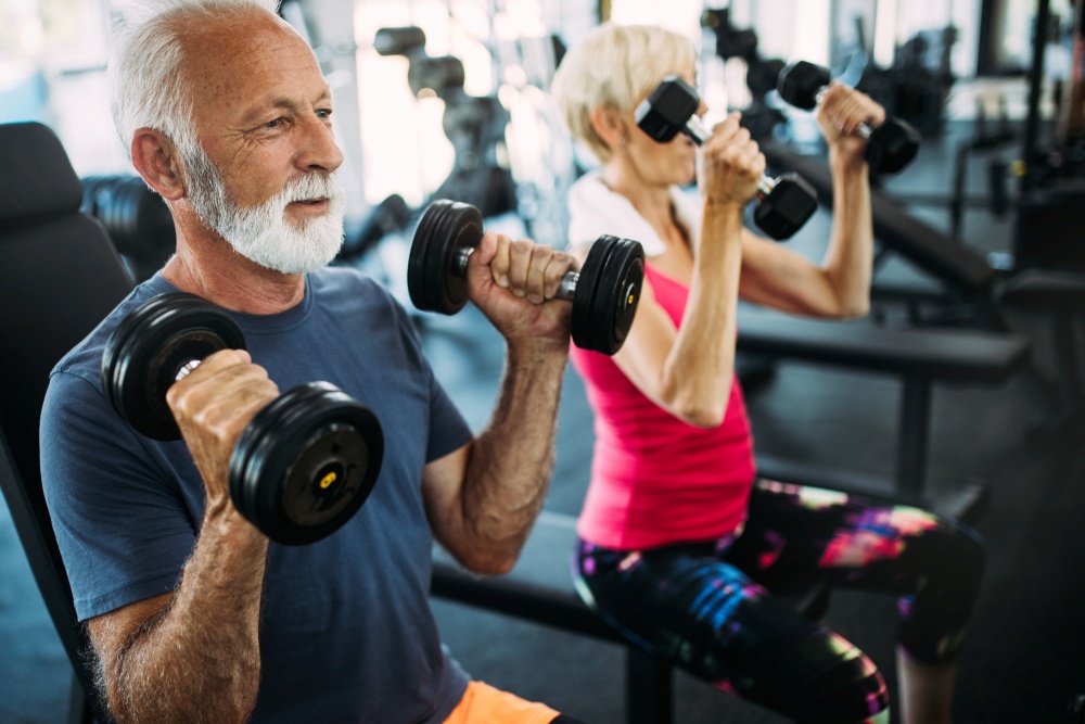 Senior fit couple exercising in gym to stay healthy