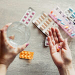 High angle view of woman's hands taking medicines at home