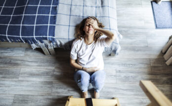 Young adult woman with depression sitting at home alone