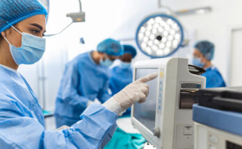 Diverse Team of Professional Surgeons Performing Invasive Surgery on a Patient in the Hospital Operating Room. Nurse Hands Out Instruments to surgeon, Anesthesiologist Monitors Vitals.