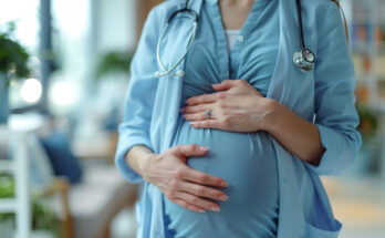 A pregnant female doctor in a blue shirt and white lab coat holding her belly, representing prenatal care and the work-life balance of women in medicine