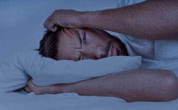 Young man lying in the bed and trying to sleep, can't sleep. Man suffering from insomnia, sleeping problems or sleep disorders