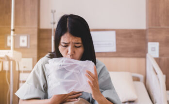 Asian woman patient puke or vomiting into plastic bag at hospital,Nausea,Indigestible